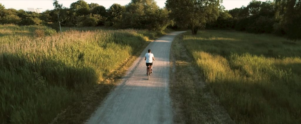 Guy biking green forest Donkey Republic sustainable bike-share